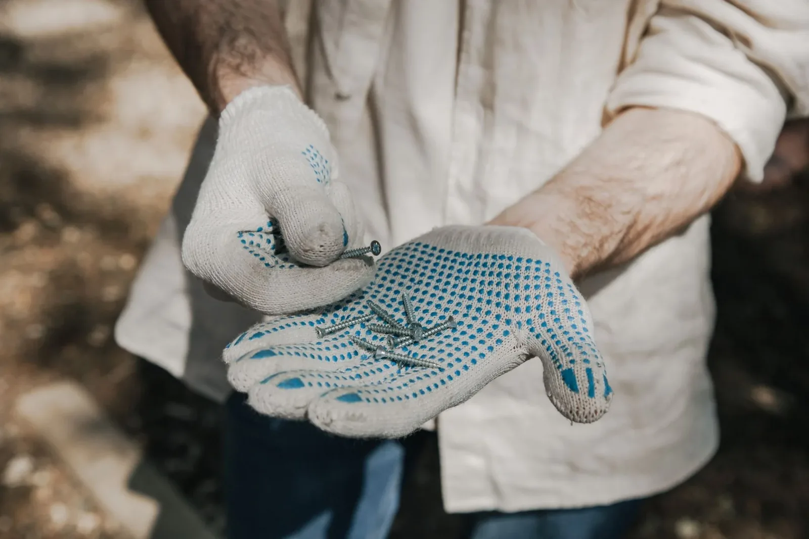 Gloved hands selecting screws before a minor repair